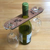 Personalised wine glass holder, meranti plywood, with hole for the nexk of the bottle and two holding places for glasses at each end - set on a wooden table