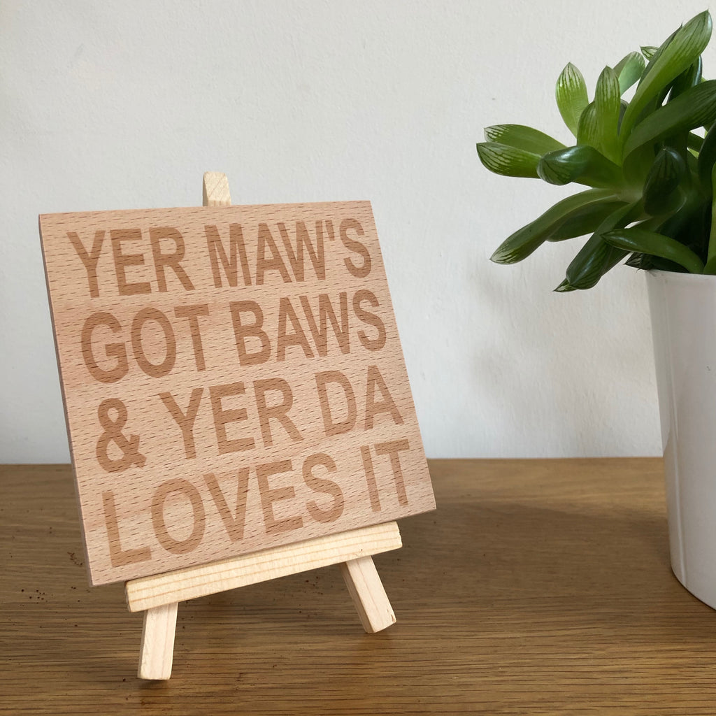 Wooden coaster gift for mothers and fathers - yer maw's got baws & yer da loves it - displayed on an easel